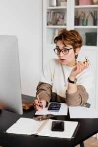 A woman writing while looking at a computer monitor